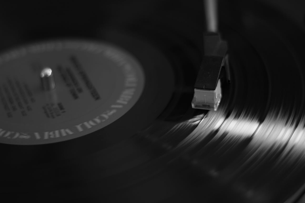 Artistic black and white close-up of a vinyl record on a turntable, emphasizing music nostalgia.